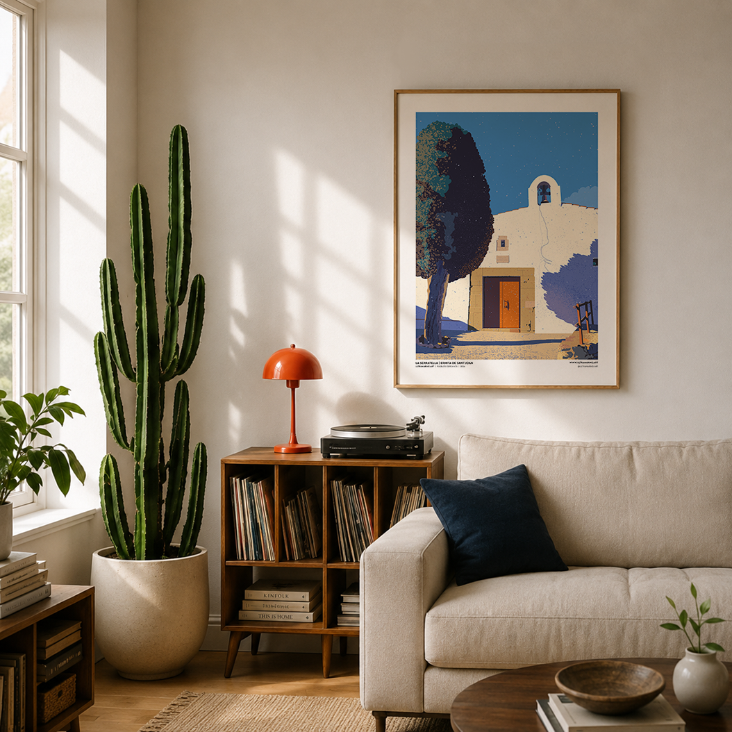 Lámina de la ermita de Sant Joan enmarcada en un salón con sofá claro y una planta cactus