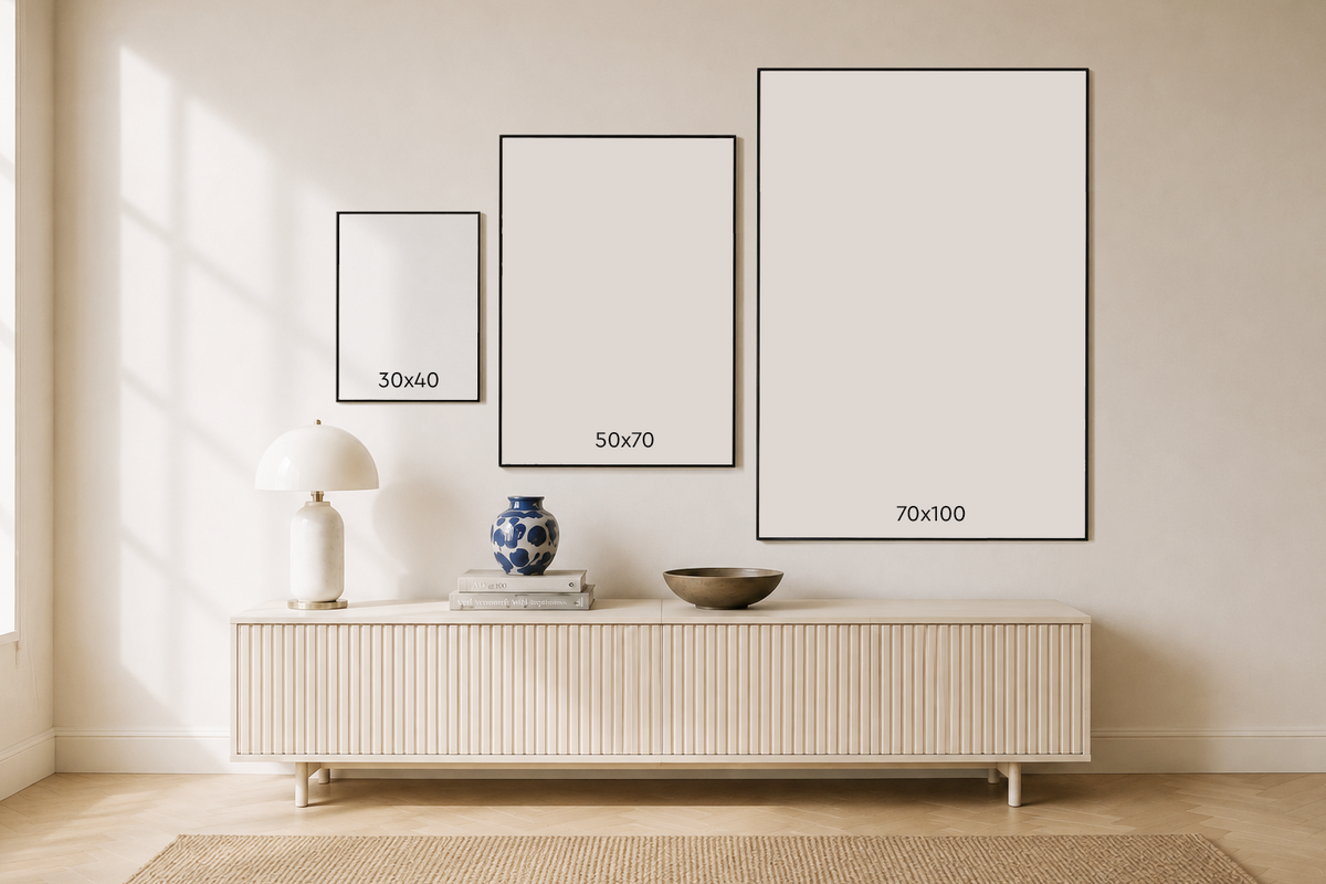Comparación de tamaños de lámina enmarcada: 30x40, 50x70 y 70x100 cm, colgadas sobre un mueble